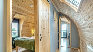 Een houten interieur met een bed, een deur en een dakraam.