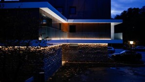 A modern building with a glass facade and a stone base. - Auberge Saint Walfrid  (Sarreguemines)