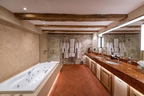 Un baño moderno con pared de piedra, una bañera grande y un tocador con dos lavamanos.