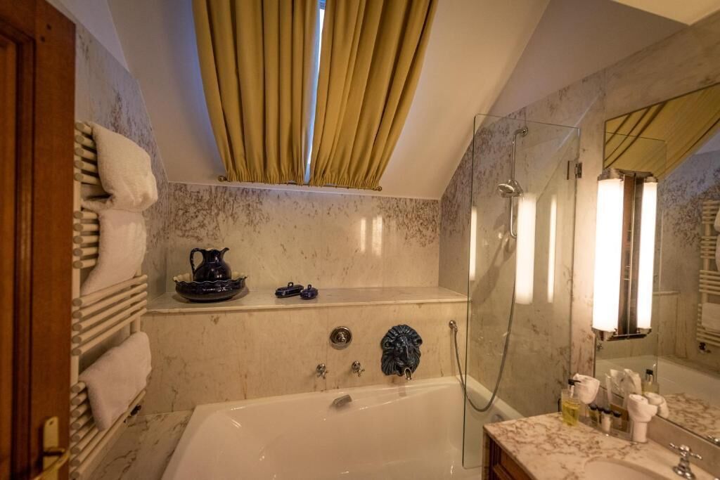 Een badkamer met een badkuip, douche, een wastafel met marmeren blad en een grote spiegel.