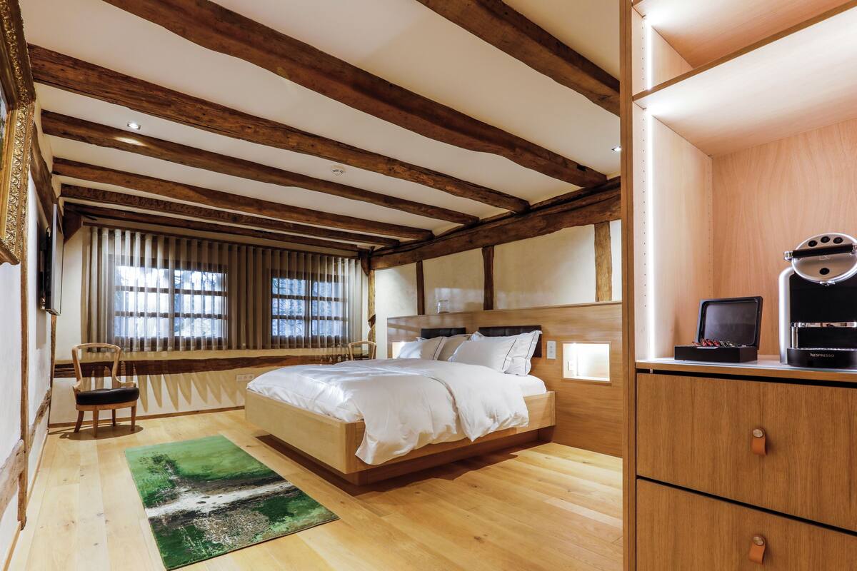 Une chambre à coucher avec un lit en bois, un bureau avec un ordinateur et une chaise.