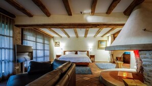 A cozy room with a bed, a leather sofa, a fireplace, and a television. - Auberge Saint Walfrid  (Sarreguemines)