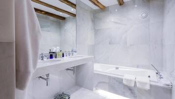 A modern bathroom with a marble sink, a bathtub, and wooden beams on the ceiling.