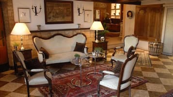 A traditional living room with a sofa, two armchairs, a coffee table, and a patterned rug.