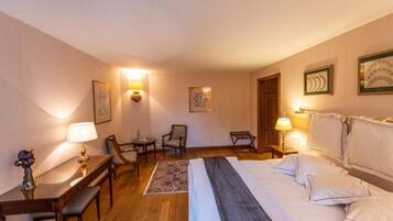 Habitación de hotel con cama, mesitas de noche, lámparas, escritorio, sillas e imágenes enmarcadas en las paredes.