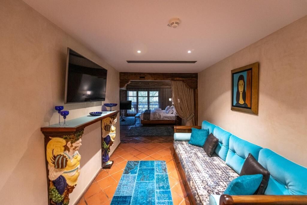 Un salon chaleureux avec un canapé bleu, un téléviseur et une statue posée sur une console.