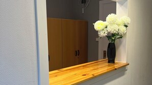A wooden shelf with a vase of flowers against a wall. - Traume Vandrarhem (Visby)