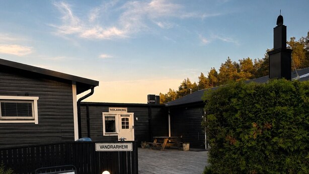 A building with a sign reading 'Solberg' and 'Vandrarhem,' gravel ground, and a hedge. - Traume Vandrarhem (Visby)