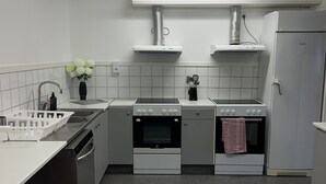 A compact kitchen with two ovens, a sink, and a refrigerator. - Traume Vandrarhem (Visby)