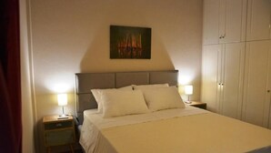 Una cama bien hecha con cabecera, dos mesitas de noche con lámparas y un cuadro en la pared.