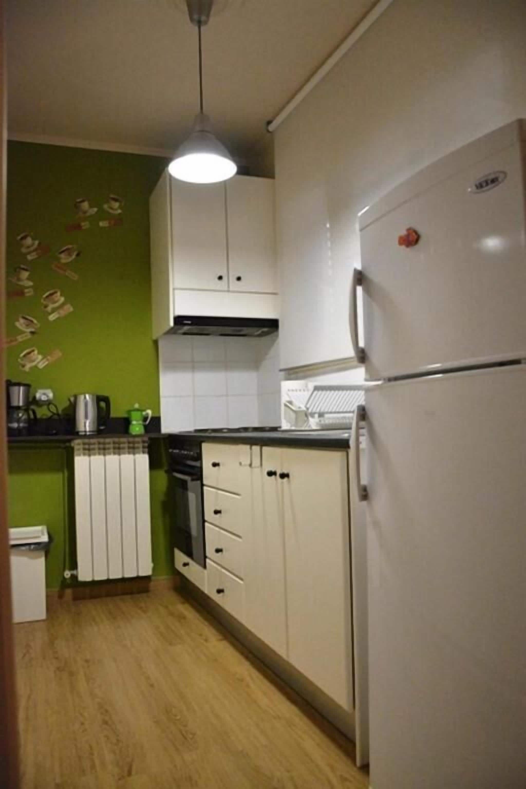 A compact kitchen with white cabinets, a built-in oven, and a refrigerator.