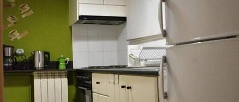 A compact kitchen with white cabinets, a built-in oven, and a refrigerator.