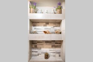 A modern kitchen with a two-tiered countertop, decorative tiles, and potted plants. - Contessa Elli Residences (Kefalonia)