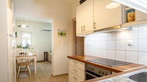 Una cocina con gabinetes blancos, encimera de madera y pileta de acero inoxidable.