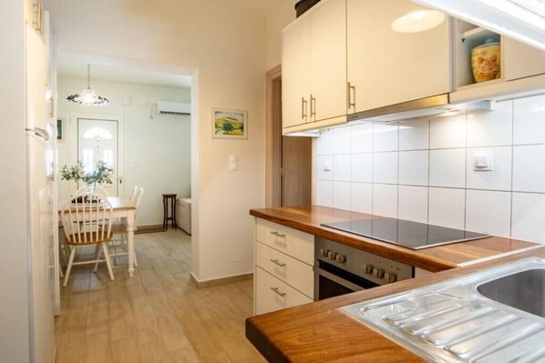 A kitchen with white cabinets, a wooden countertop, and a stainless steel sink.