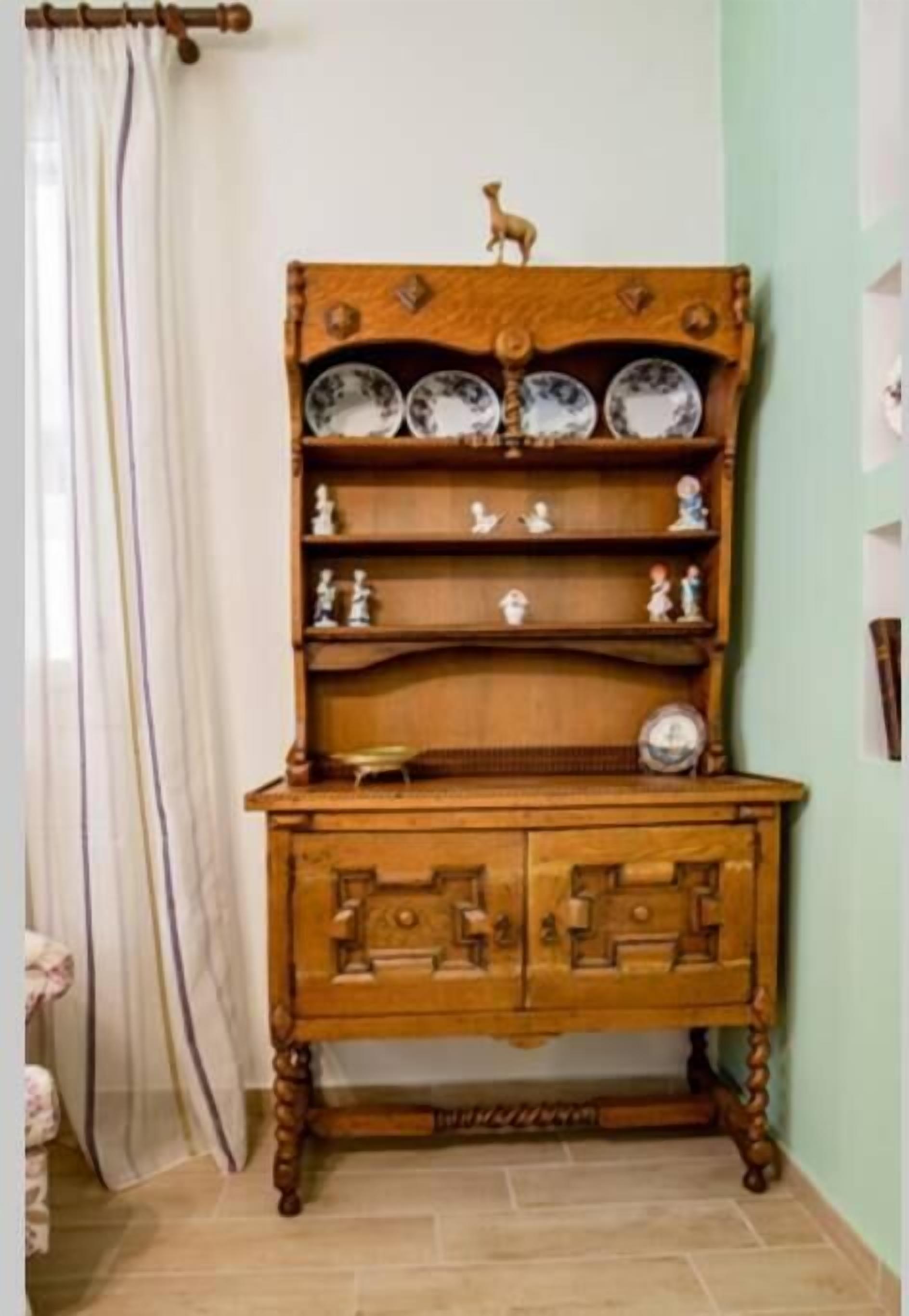 Un meuble en bois doté de plusieurs étagères et de tiroirs, agrémenté d’assiettes décoratives et de figurines.