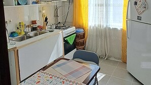 A compact kitchen with a dining area, a stove, a sink, and a refrigerator. - Cozy & Stylish Suite room with a Garden view in Batumi (BATUMI)