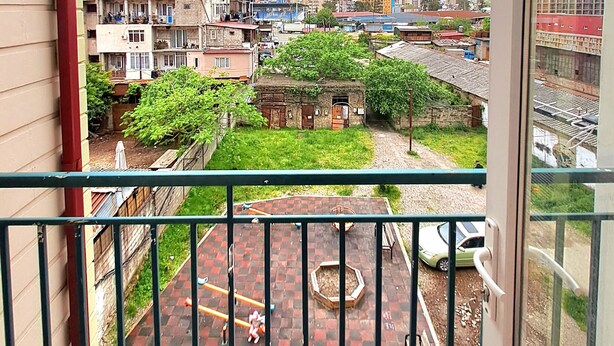 A balcony with a view of a courtyard, including a playground and a small building. - Cozy & Stylish Suite room with a Garden view in Batumi (BATUMI)