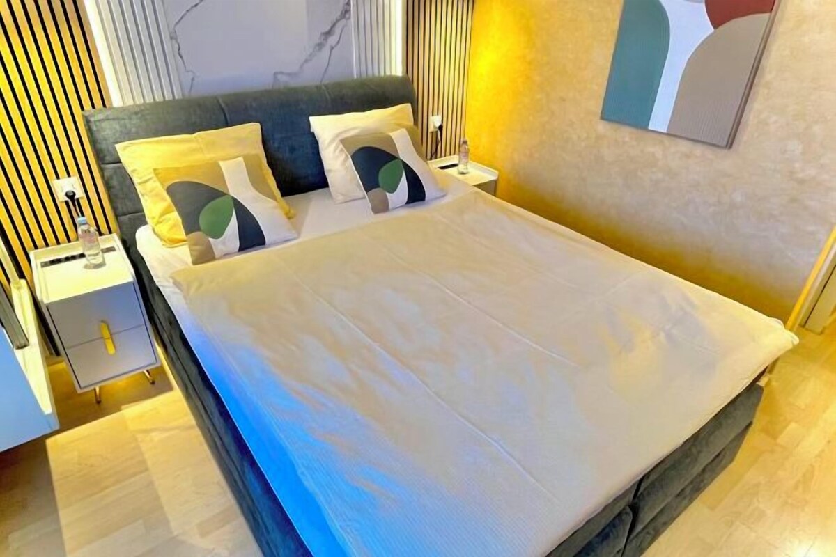Un dormitorio moderno con una cama grande, mesitas de noche y una obra de arte colgada en la pared.