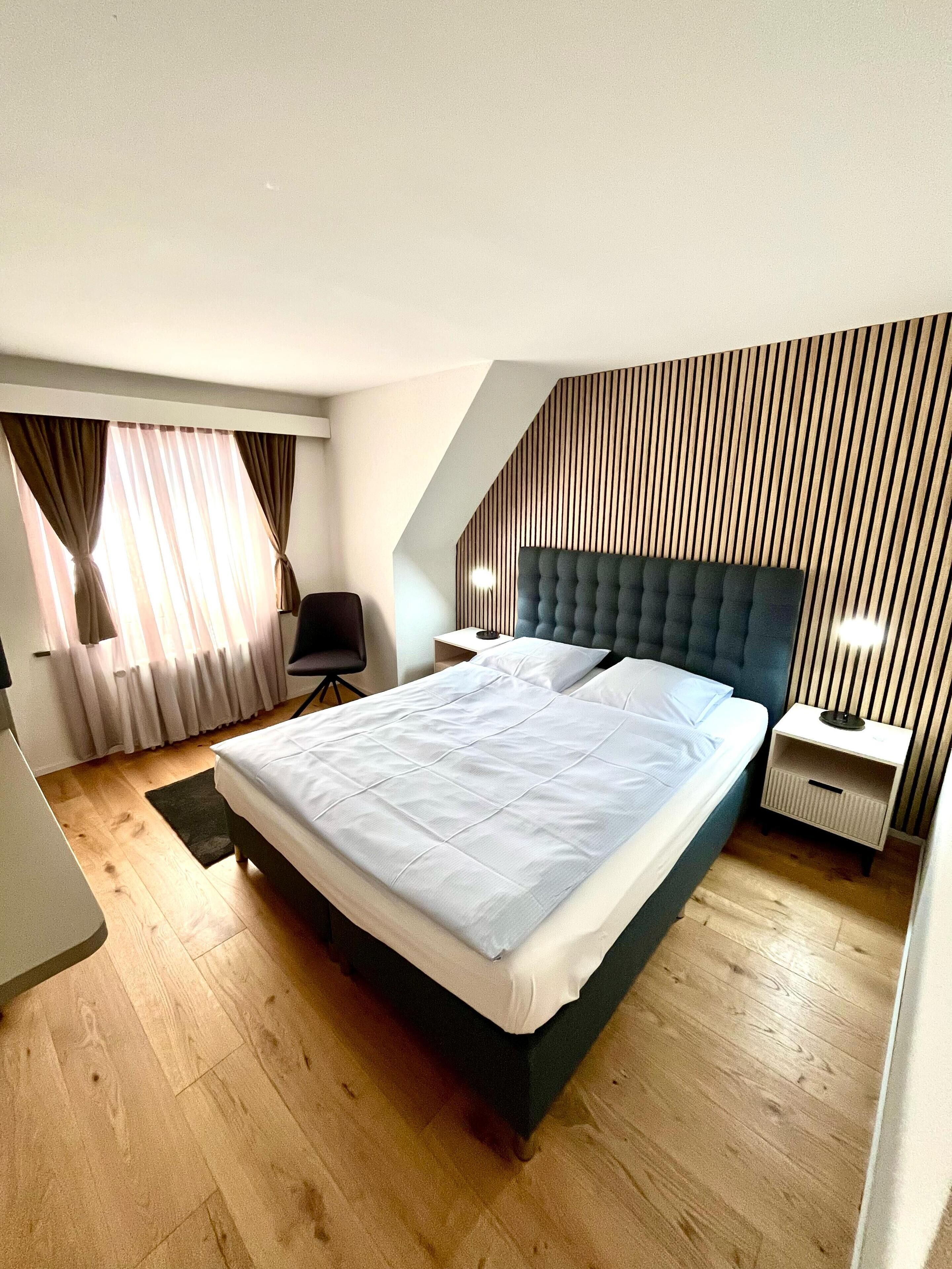 Ein modernes Schlafzimmer mit einem großen Bett, einem Schreibtisch und einem Sessel.