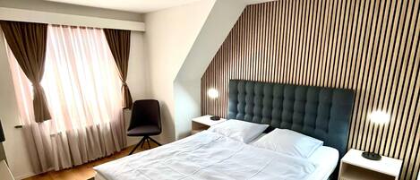 Ein modernes Schlafzimmer mit einem großen Bett, einem Schreibtisch und einem Sessel.