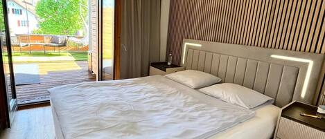 Una habitación de hotel moderna con una cama grande, suelo de madera, vistas al exterior y un diseño de pared a rayas.