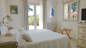 Une chambre à coucher avec un grand lit, une table de chevet, une chaise, un radiateur et une fenêtre donnant sur des arbres.