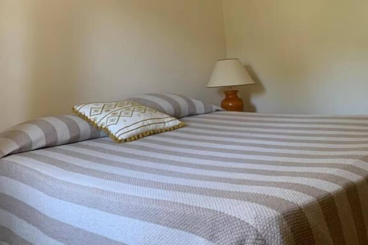 Une chambre à coucher avec un lit, une lampe et une structure en poutres apparentes.