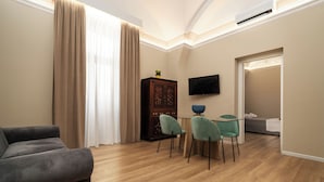 A modern living room with a sofa, dining table, chairs, and a TV. - Archimedes suites  (Catania)