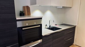A modern kitchen with dark cabinetry, a Bosch oven, a stainless steel sink, and a white countertop. - Cozy Flats Silkeborg - S3 (Silkeborg)