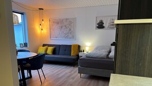 A modern living room with a sofa, a dining table, and a lamp. - Cozy Flats Silkeborg - S3 (Silkeborg)