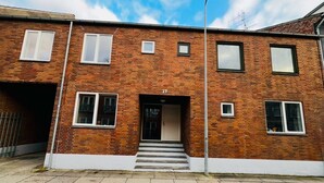 A two-story brick building with a garage door, numbered 17, and a set of stairs leading to the entrance. - Cozy Flats Silkeborg - S3 (Silkeborg)