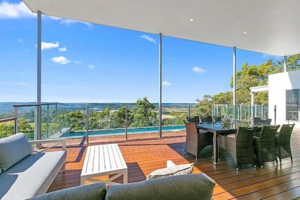 Une terrasse extérieure moderne comprenant un espace repas, une piscine et une vue sur le paysage.