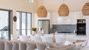 A modern kitchen with white cabinets, a stainless steel refrigerator, and a tiled backsplash. - Cooinda Luxury Residence and Studio (Valdora)