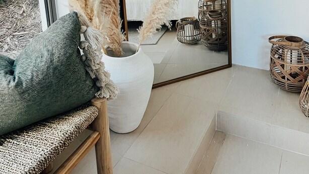 A modern bedroom with a large mirror, a bed, and decorative plants.