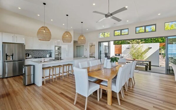 Una cocina moderna con una isla central, electrodomésticos de acero inoxidable e iluminación colgante.