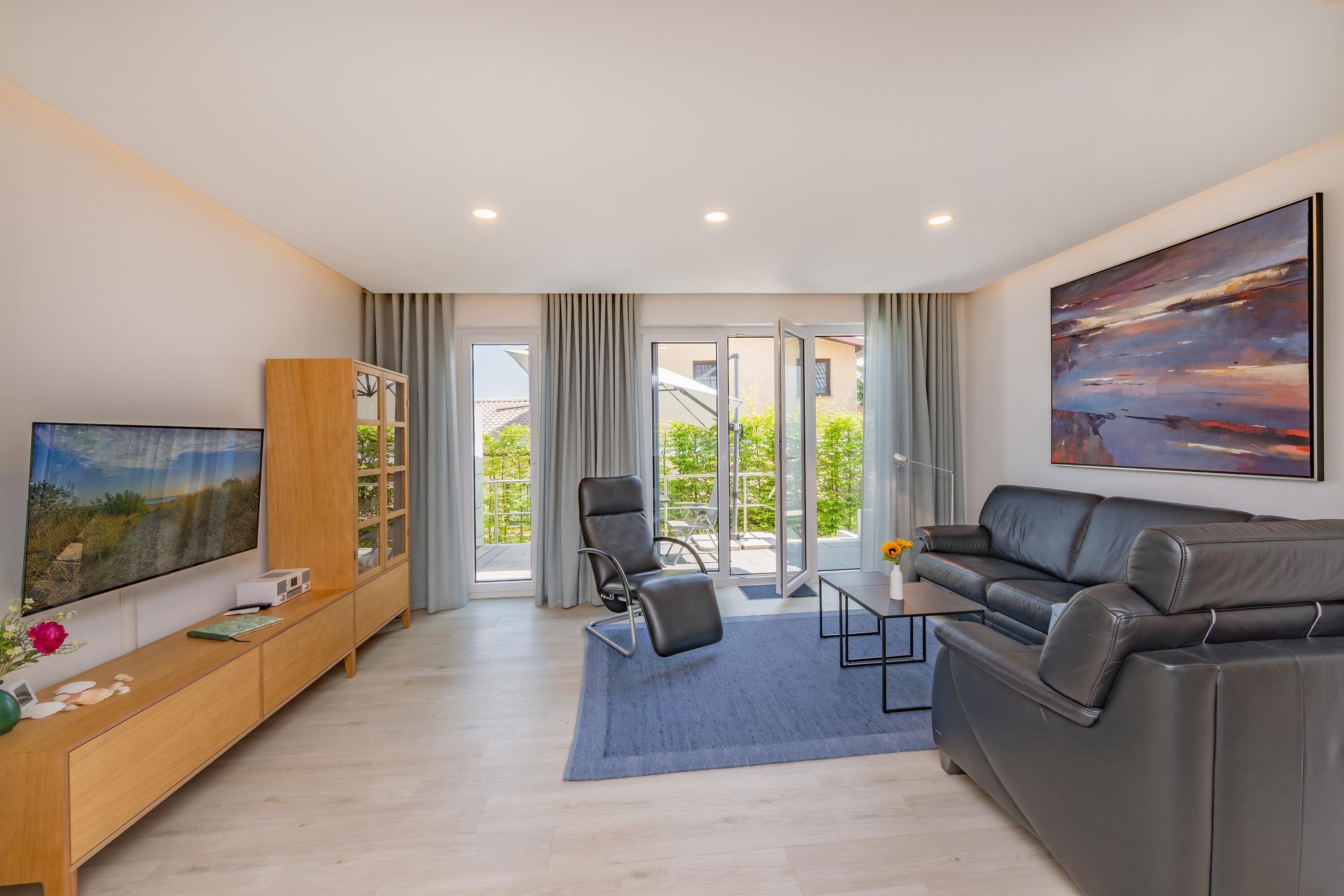 A modern living room with a sofa, a TV, a bookshelf, and a painting.