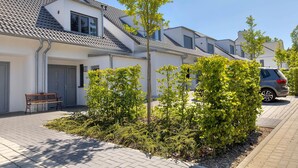 Een woonwijk met moderne huizen, een verhard voetpad en een geparkeerde auto.