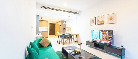 Una sala de estar moderna con un sofá verde, una mesa de centro, un televisor de pantalla plana y obras de arte en la pared.