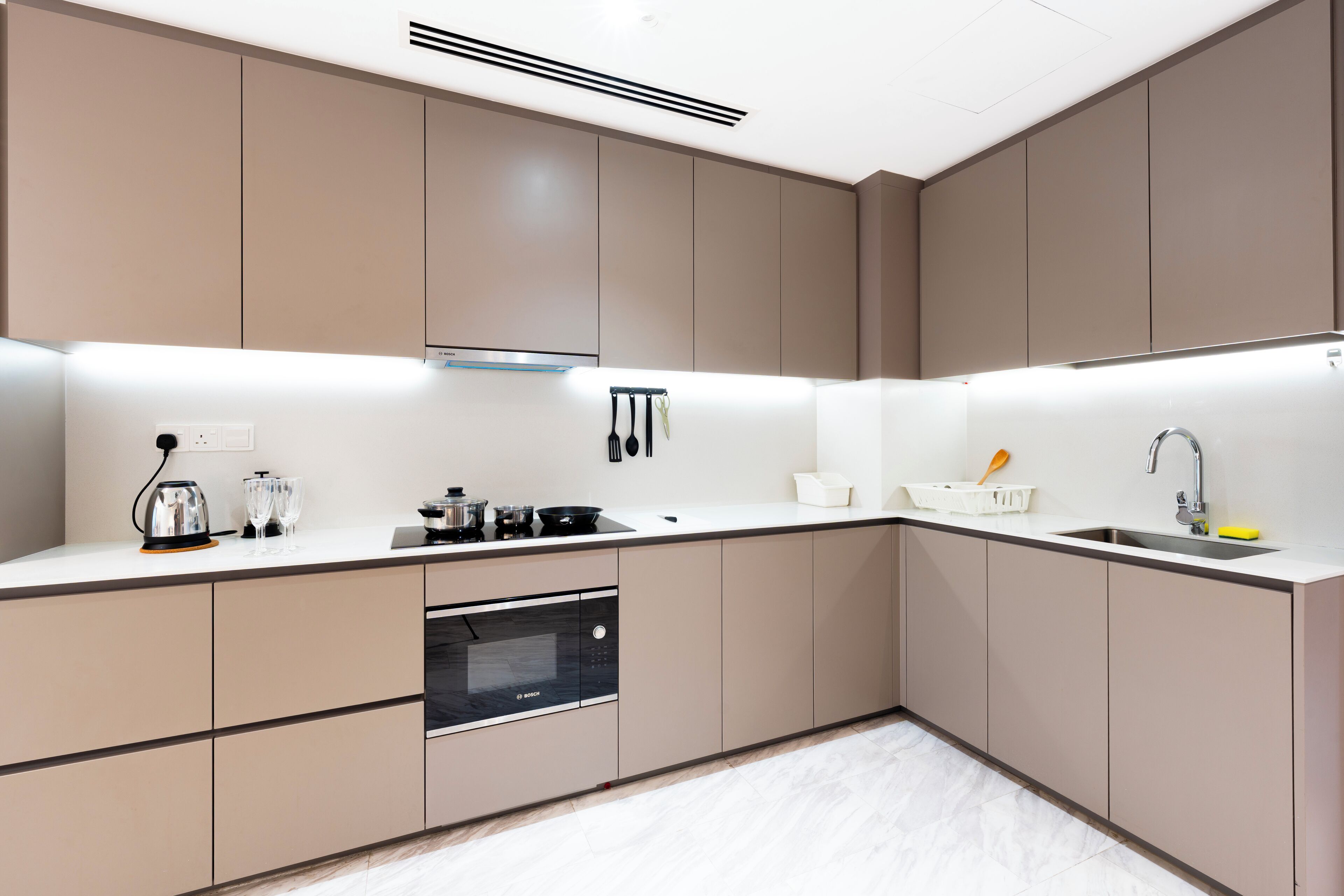 A modern kitchen with built-in appliances, a white countertop, and beige cabinetry.