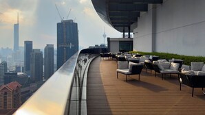 Een terras op het dak met buitenmeubels en uitzicht over de stad.