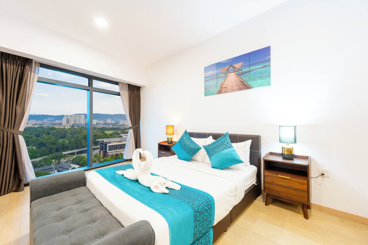 Habitación de hotel con un gran ventanal, una cama con vistas, una mesita de noche y un cuadro en la pared.
