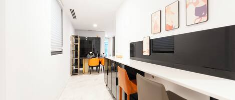 A modern kitchen with a white countertop, orange chairs, and a black backsplash.