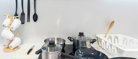 A kitchen with a stove, pots, a cutting board, and utensils.