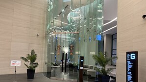 Eine moderne Lobby mit Glaswänden, einem Briefkasten und einem Hinweisschild.