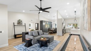 A modern living room with a grey sofa, black coffee table, and a shuffleboard table. - Private Pool, Hot Tub & Putting Green Home (Scottsdale)