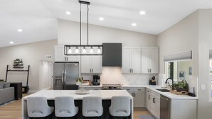 A modern kitchen with a central island, bar stools, a built-in oven, and a large window. - Private Pool, Hot Tub & Putting Green Home (Scottsdale)