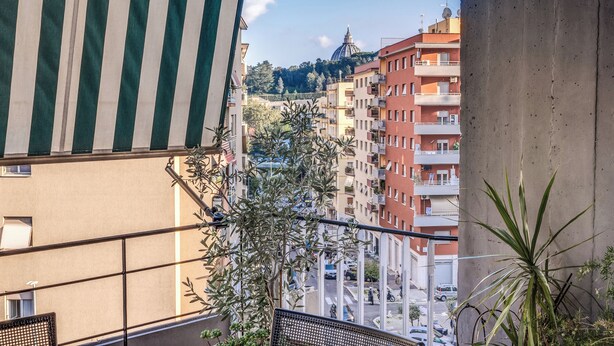 A view from a balcony overlooking a city street with buildings, a dome structure, and a clear sky. - Musei Vaticani Apartamento per 8 persone (Rome)