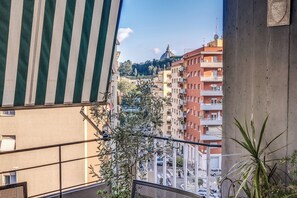 Udsigt fra en balkon over et bybillede med bygninger, en kuppel og en klar himmel.