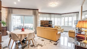 A spacious living area with a marble floor, a round dining table with chairs, a sofa, and a television. - Musei Vaticani Apartamento per 8 persone (Rome)